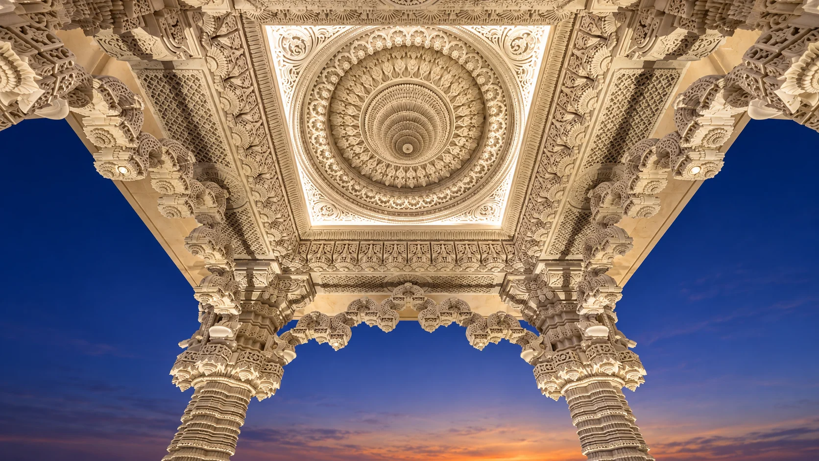 Резной навес BAPS Mandir с круглым каменным узором на фоне вечернего неба