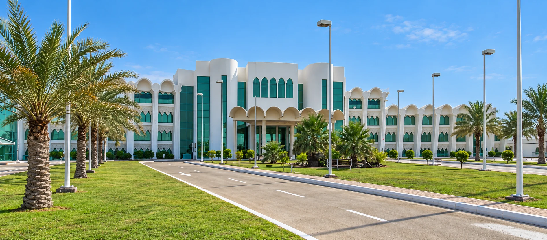 Белый фасад Mirfa Hotel с арочным входом и пальмами у подъездной дороги