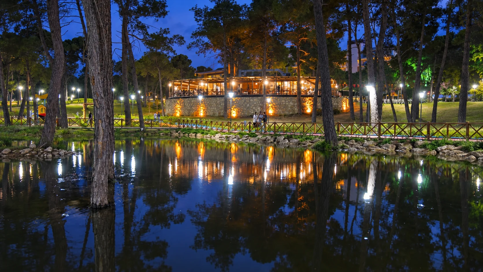 Вечерний Belek Park Orman: подсвеченный павильон и сосны отражаются в пруду