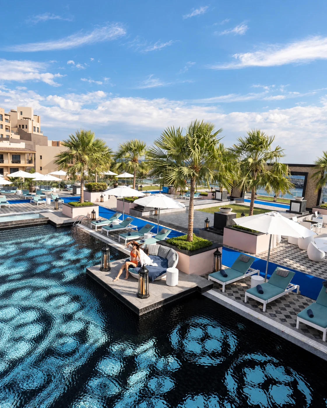 Терраса бассейна Fairmont Fujairah с пальмами и голубыми лежаками