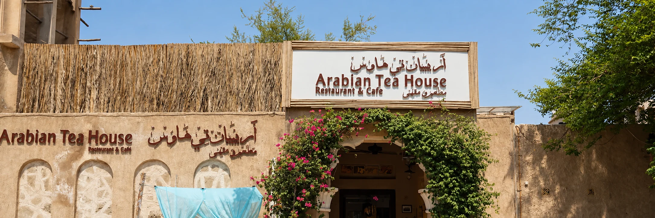 Вход Arabian Tea House в Аль-Фахиди с зеленью и вывесками