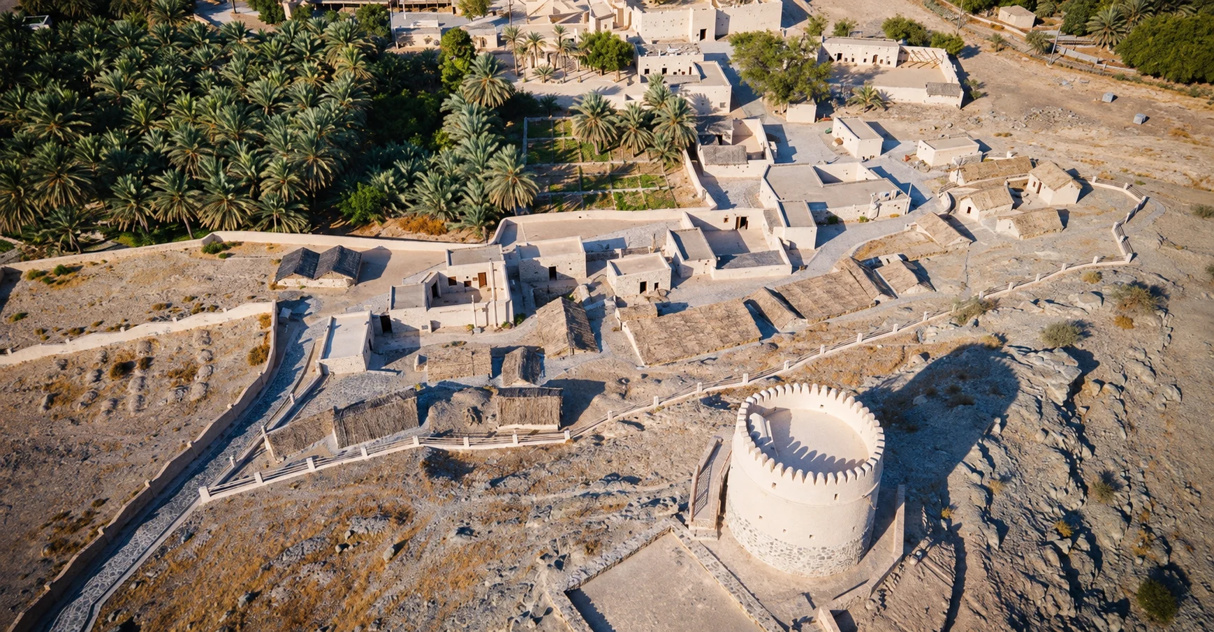 Восстановленные постройки Heritage Village и круглая башня на каменистом склоне